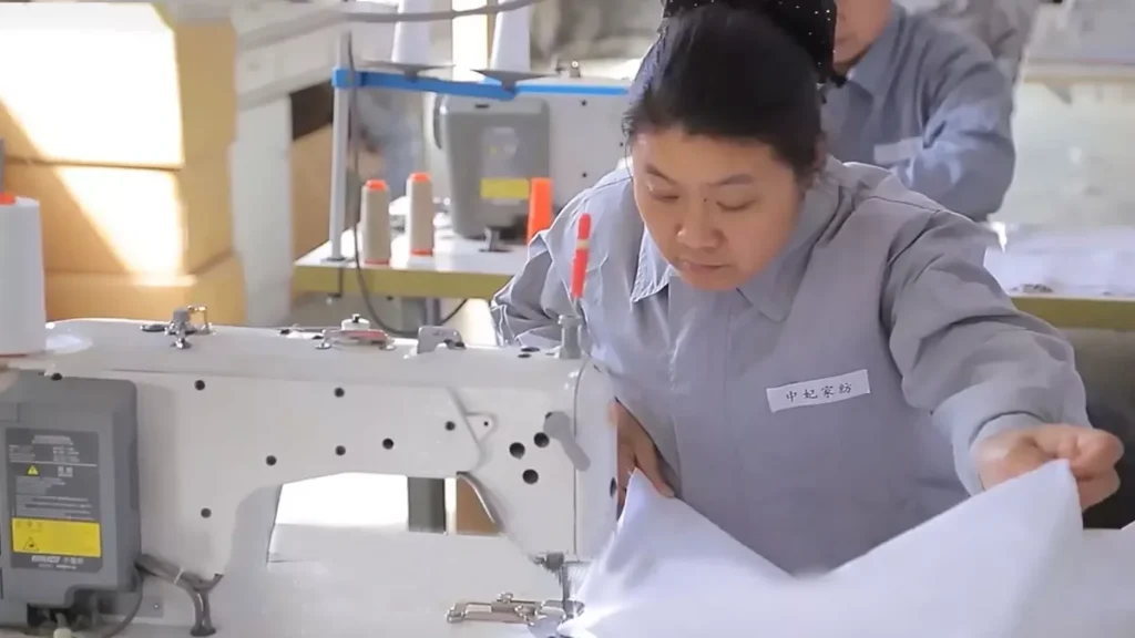 Close-up of a sewing machine stitching white cotton bedding